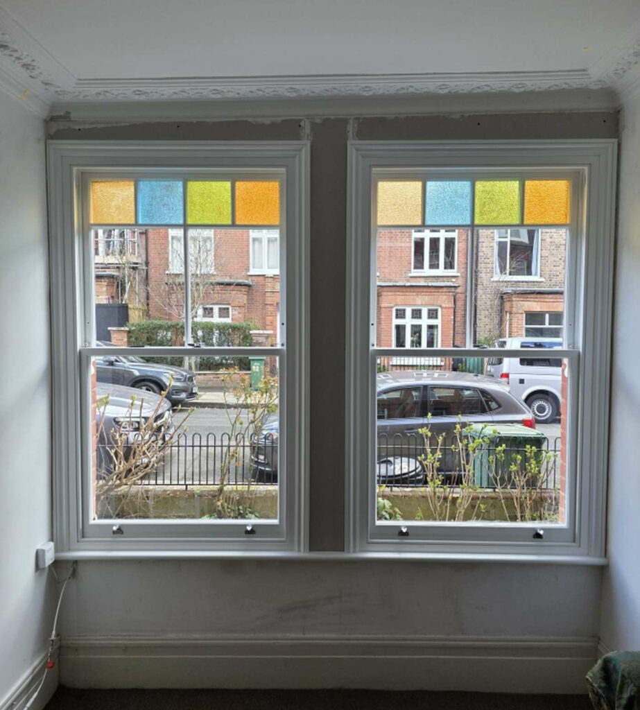 Timber sash windows with coloured top lights in a London period room