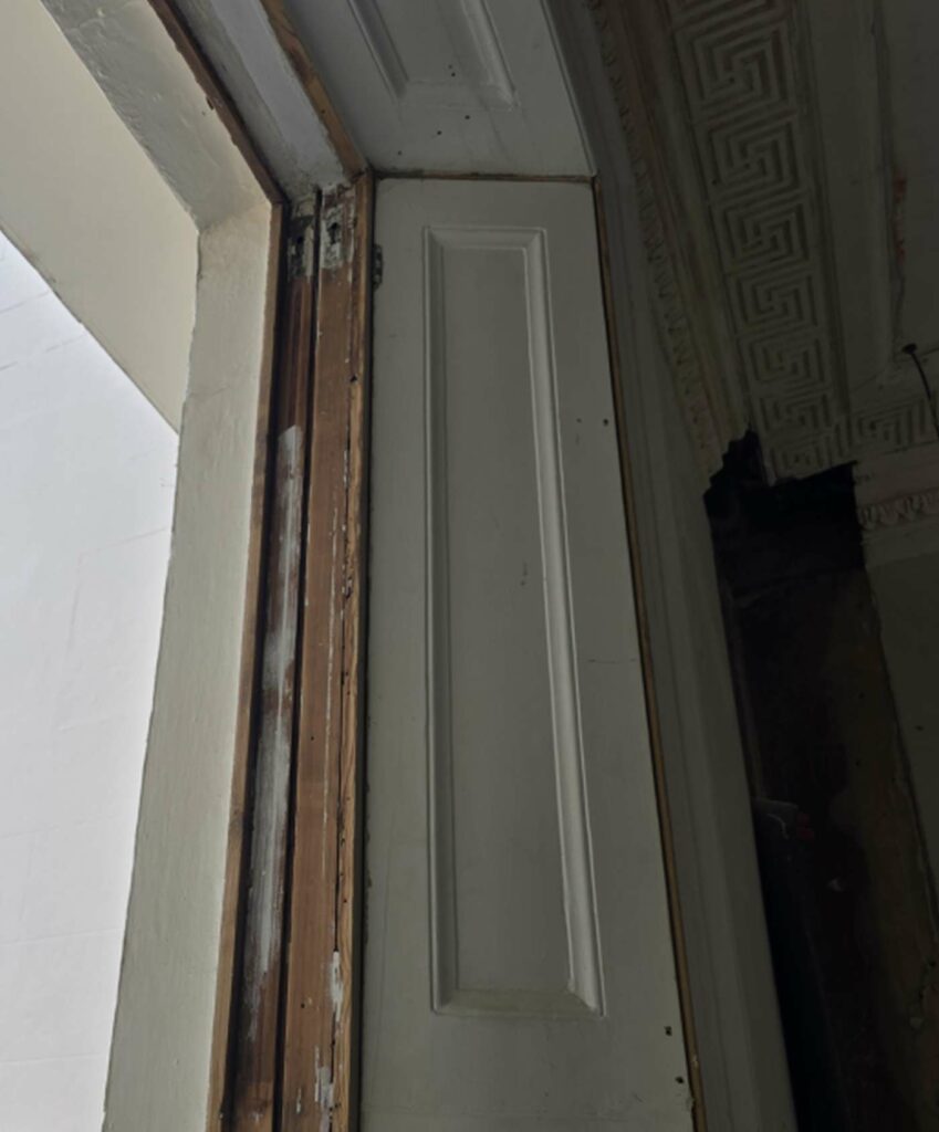 Exposed timber sash window box frame beside internal period panelling