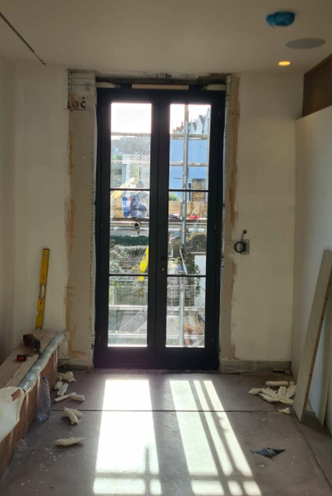 New timber French door being installed in a former sash window opening