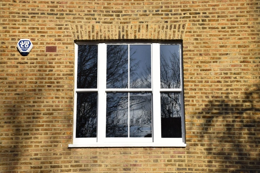 Traditional white timber sash window set in a brick London property