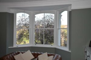 Three white timber sash windows forming a bay in a London home
