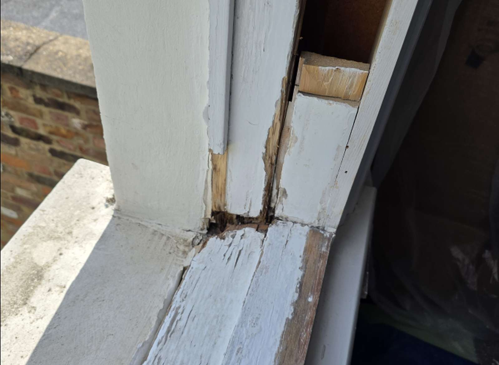 Local timber decay exposed at the lower joint of a sash window during inspection