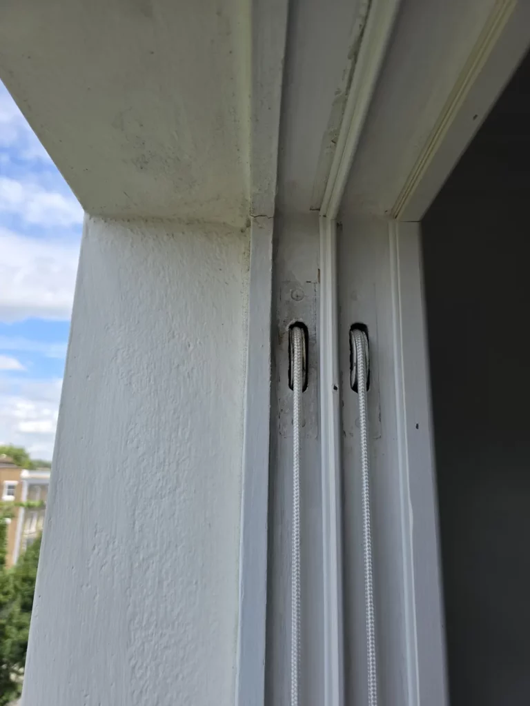 Two sash cords passing through pulley openings in a timber box frame
