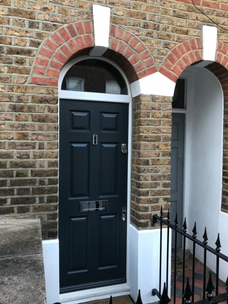Dark-painted panelled timber front door beneath a brick arch