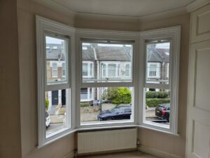 White-painted sash windows in a bay overlooking a residential street