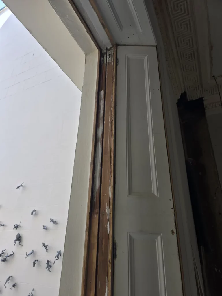 Exposed timber sash box frame beside a panelled internal shutter