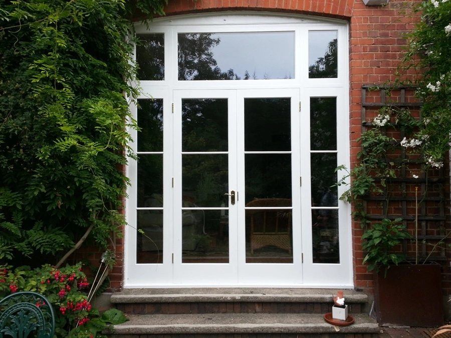 White-painted French doors with glazed sidelights and a transom